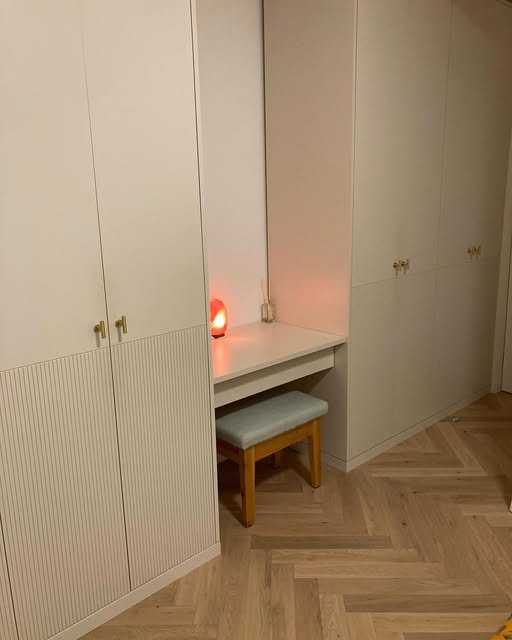 Tall fitted wardrobe with pale doors and wood trim.